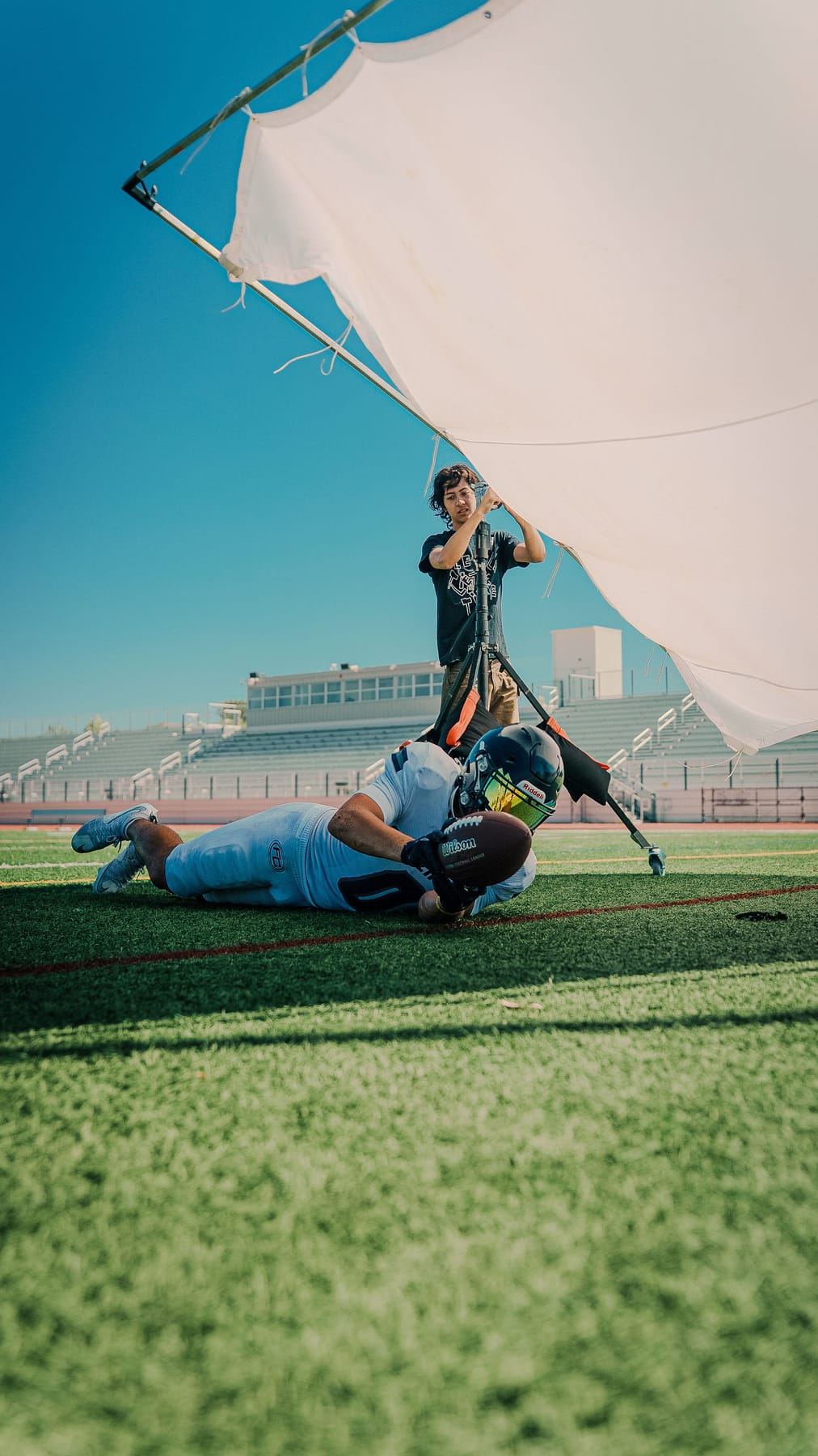 Football player securing a catch on the turf under a diffusion silk